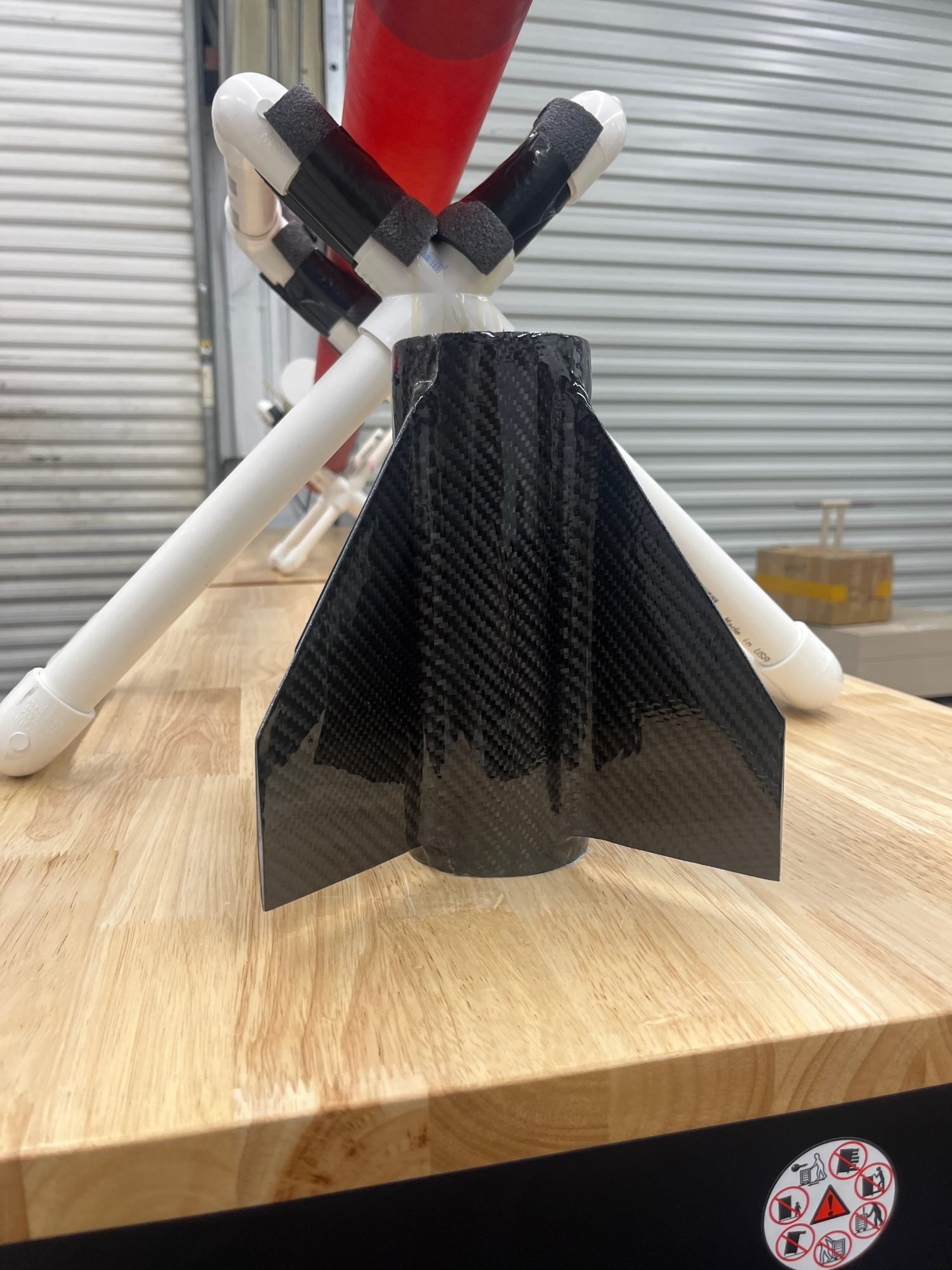 A carbon fiber fin can resting on a stand on a shop workbench