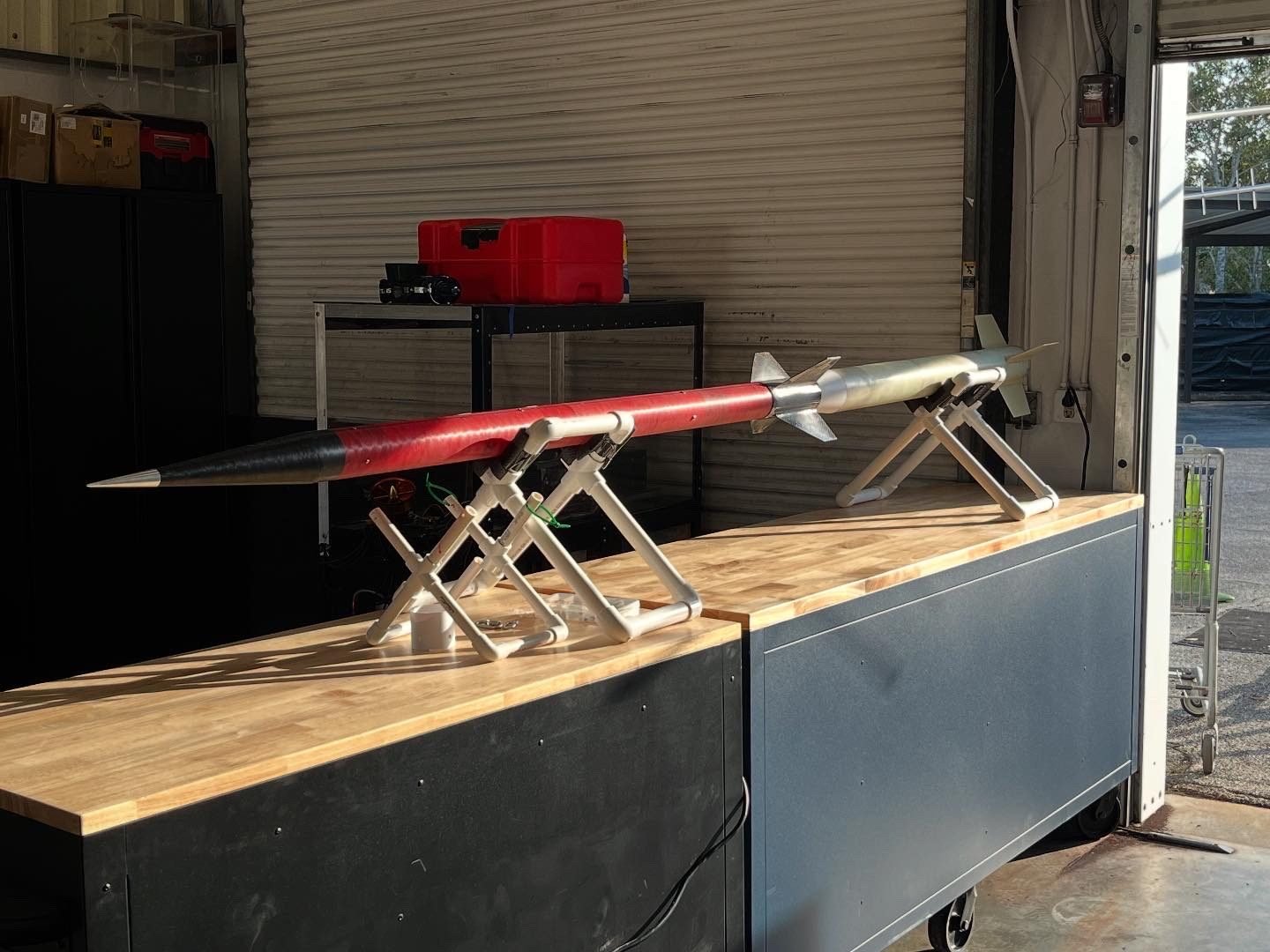 A red and black rocket resting on stands on a workbench